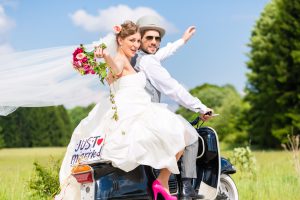 Brautpaar frisch verheiratet und glücklich auf dem Motorroller Richtung Zukunft